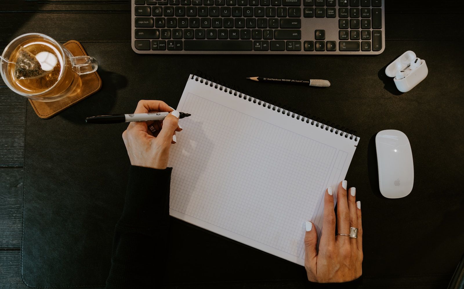 A notebook beside a keyboard, photographed by Kelly Sikkema on Unsplash.